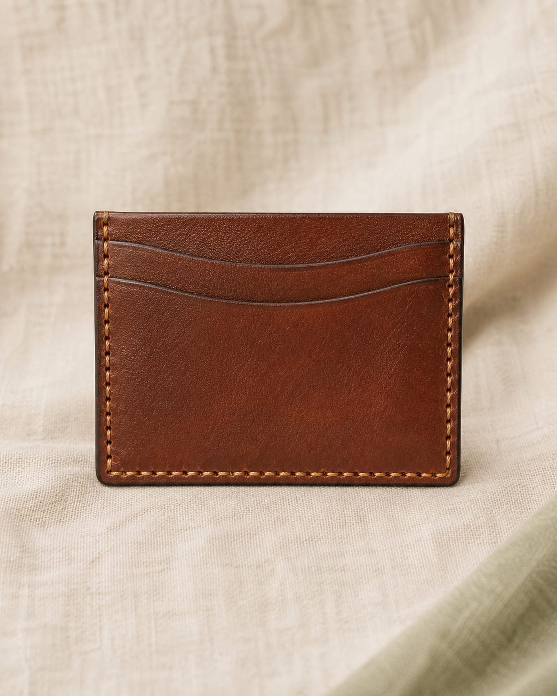 Chestnut slim leather card holder on ivory linen.