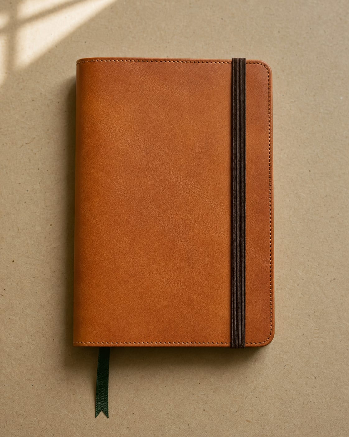 Closed tan leather journal cover with green ribbon bookmark.