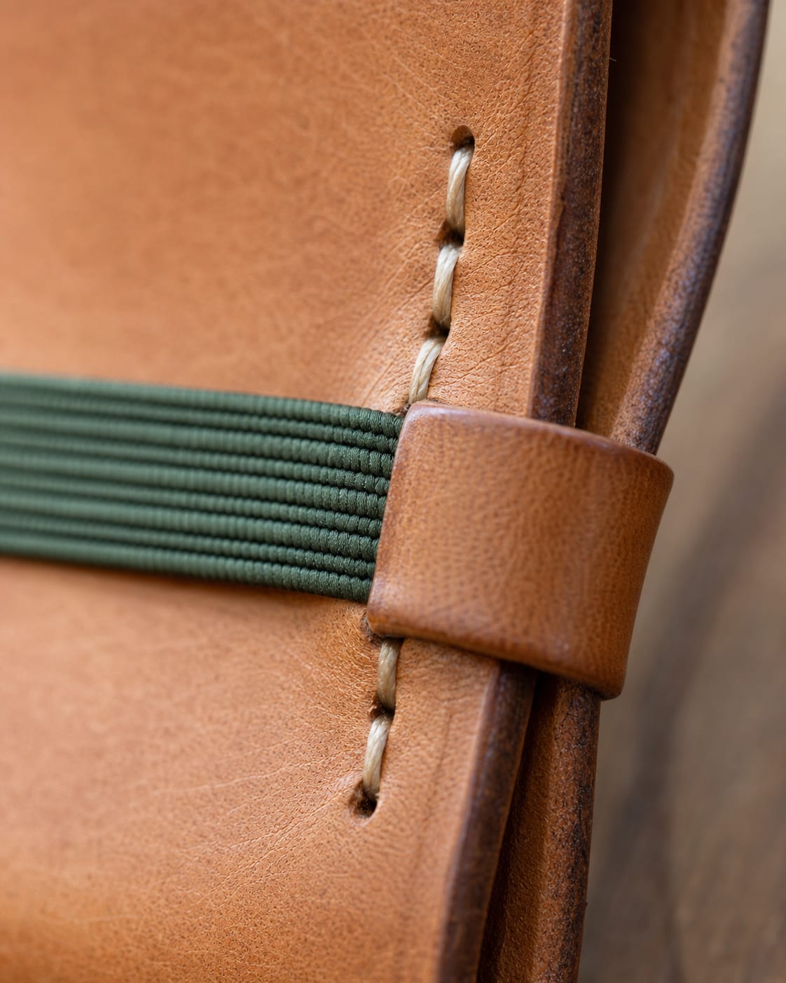 Close-up of elastic closure stitched to a leather journal cover.